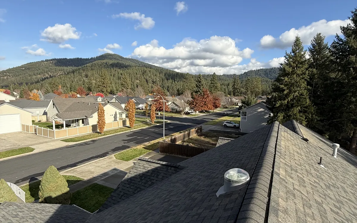 Finished architectural shingle roof overlooking a neighborhood and forested hills