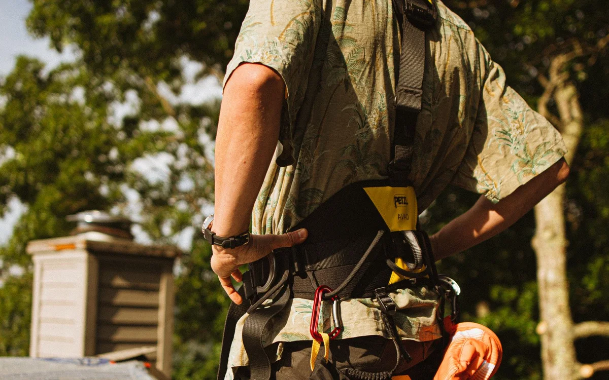 Roofer wearing a fall-protection harness on a roof next to a chimney