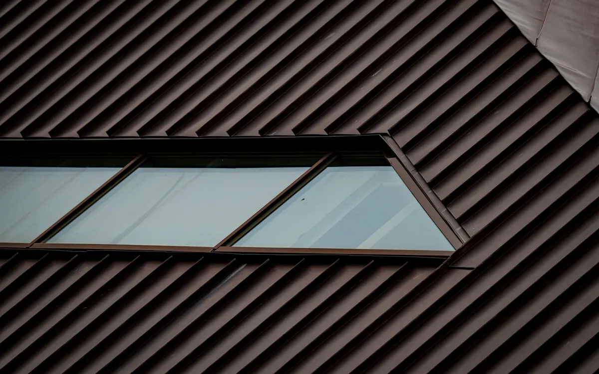 Close-up of a dark standing seam metal roof with a skylight