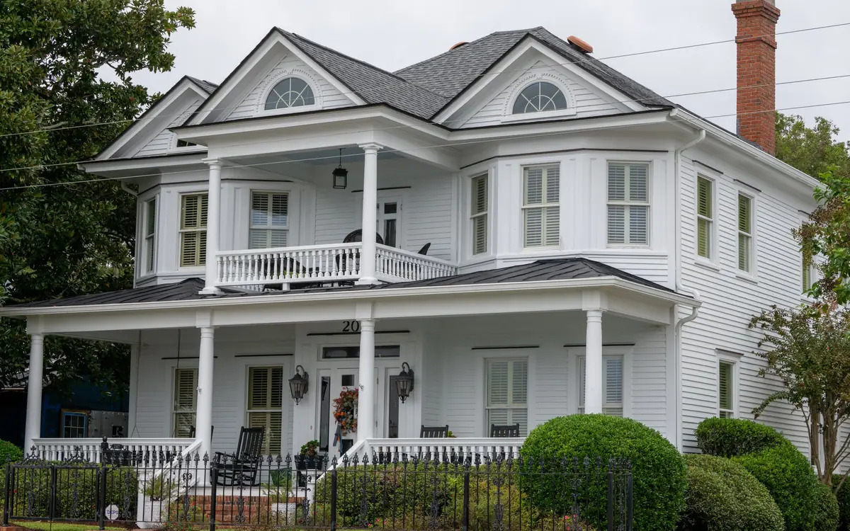 White two-story house with a standing seam metal roof over the wraparound porch