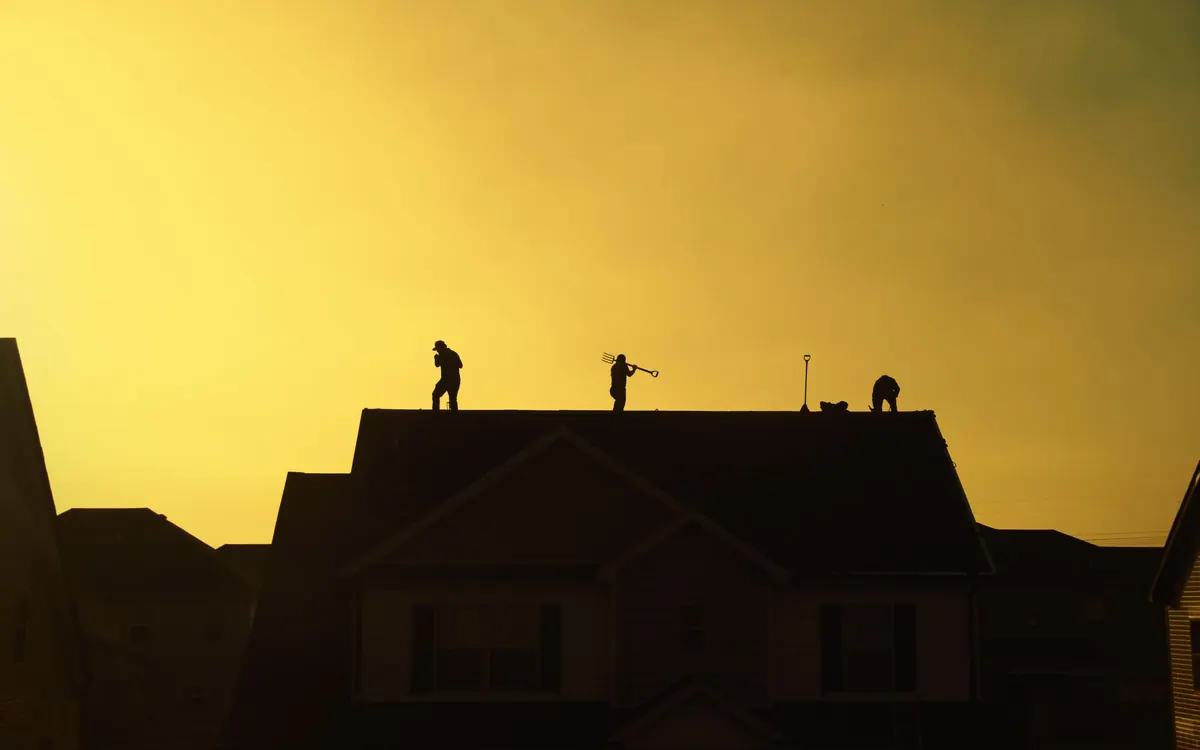 Silhouettes of roofers working on a roof at sunset