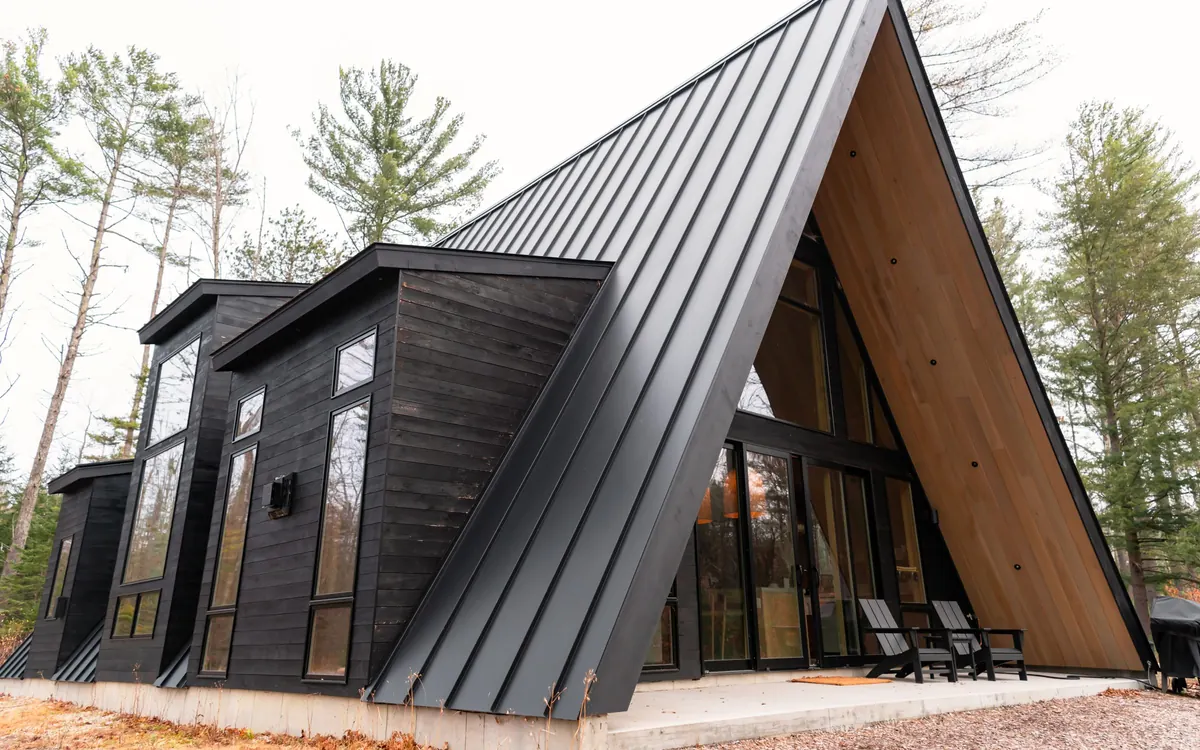 A-frame house with a black standing seam metal roof in the woods